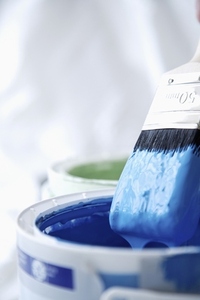 Close up of blue paint pot and dripping paintbrush