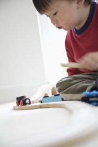 Young boy playing with wooden train set