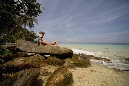 Back of young woman lying on rocks sunbathing and relaxing Koh Phi Phi Thailand