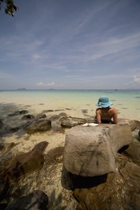 Young woman lying on rocks sunbathing and relaxing Koh Phi Phi Thailand