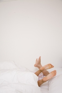 Two pairs of feet coming out white duvet