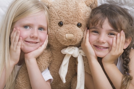 Close up of two young girls with teddy bear smiling