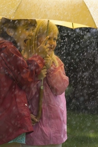 Two young girls in the rain under yellow umbrella