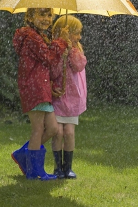 Two young girls in the rain under yellow umbrella