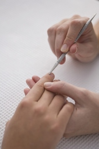 Close up of manicurist039 s hand pushing woman039 s cuticles with cuticle pusher