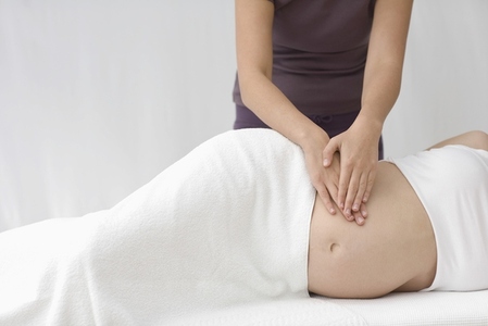 Female massage therapist039 s hands massaging pregnant woman stomach