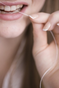 Close up of young woman flossing front teeth