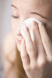 Close up of young woman removing make up with white cotton pad