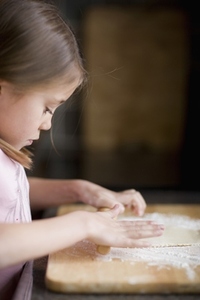 Young girl rolling dough on table