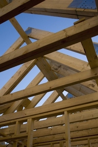Roof beams of house under construction against blue sky