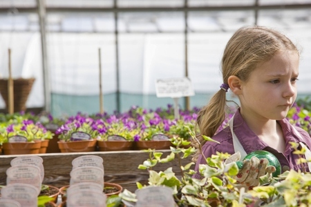 Portrait of young girl amongst flowerpots inside greenhouse