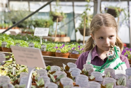 Portrait of young girl amongst flowerpots inside greenhouse