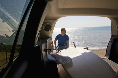 Portrait of a young man sitting with his back to the ocean shot from inside car