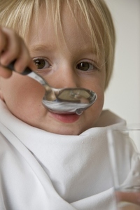 Close up of young blonde boy drinking water with a spoon