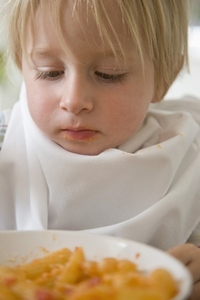 Close up of young blonde boy looking at a bowl of pasta