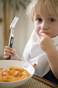 Portrait of young blonde boy eating pasta