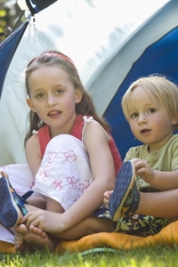 Portrait of boy and girl sitting by tent
