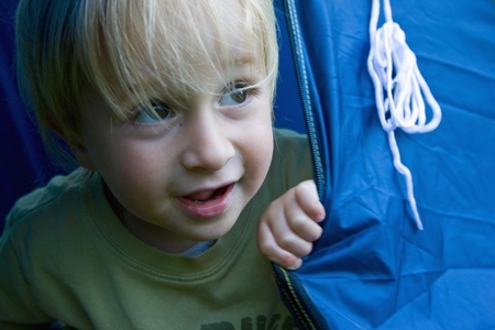 Young blonde boy playing inside a tent