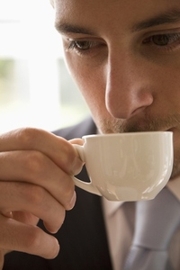 Close up of young businessman drinking and holding coffee cup