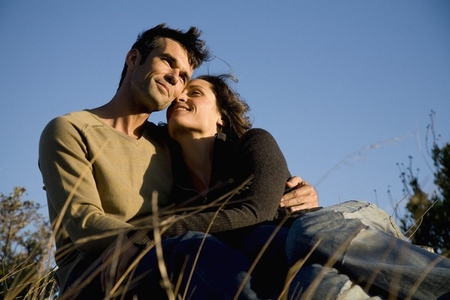 Portrait of couple embracing sitting on field