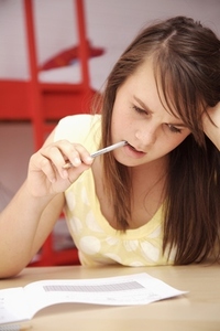 Young girl studying with pencil in mouth