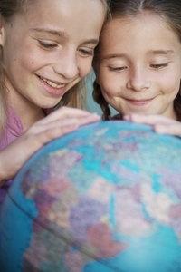 Two young girls touching and spinning  a world globe