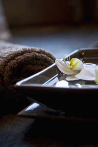 White flowers floating in square bowl with brown towels