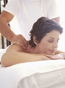 Male massage therapist massaging woman on shoulders outdoors