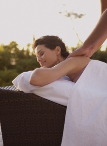 Male massage therapist massaging woman on shoulders outdoors