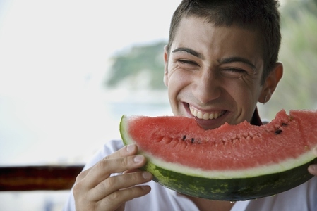Young man eating water melon and laughing