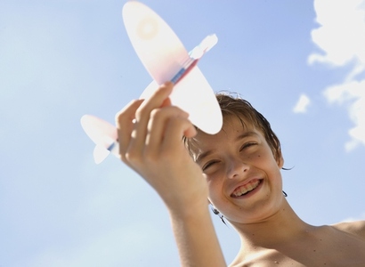 Young boy holding model aeroplane against blue sky