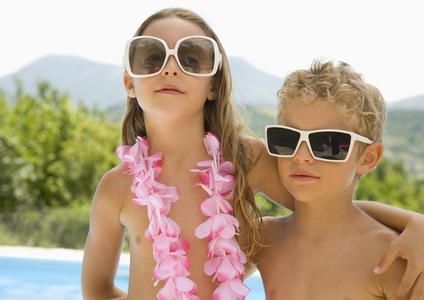 Young boy and young girl wearing oversized sunglasses