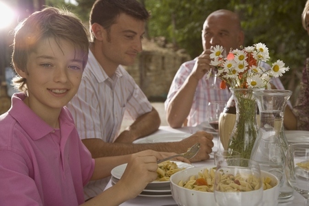 Family having pasta meal with smiling young boy in the foreground