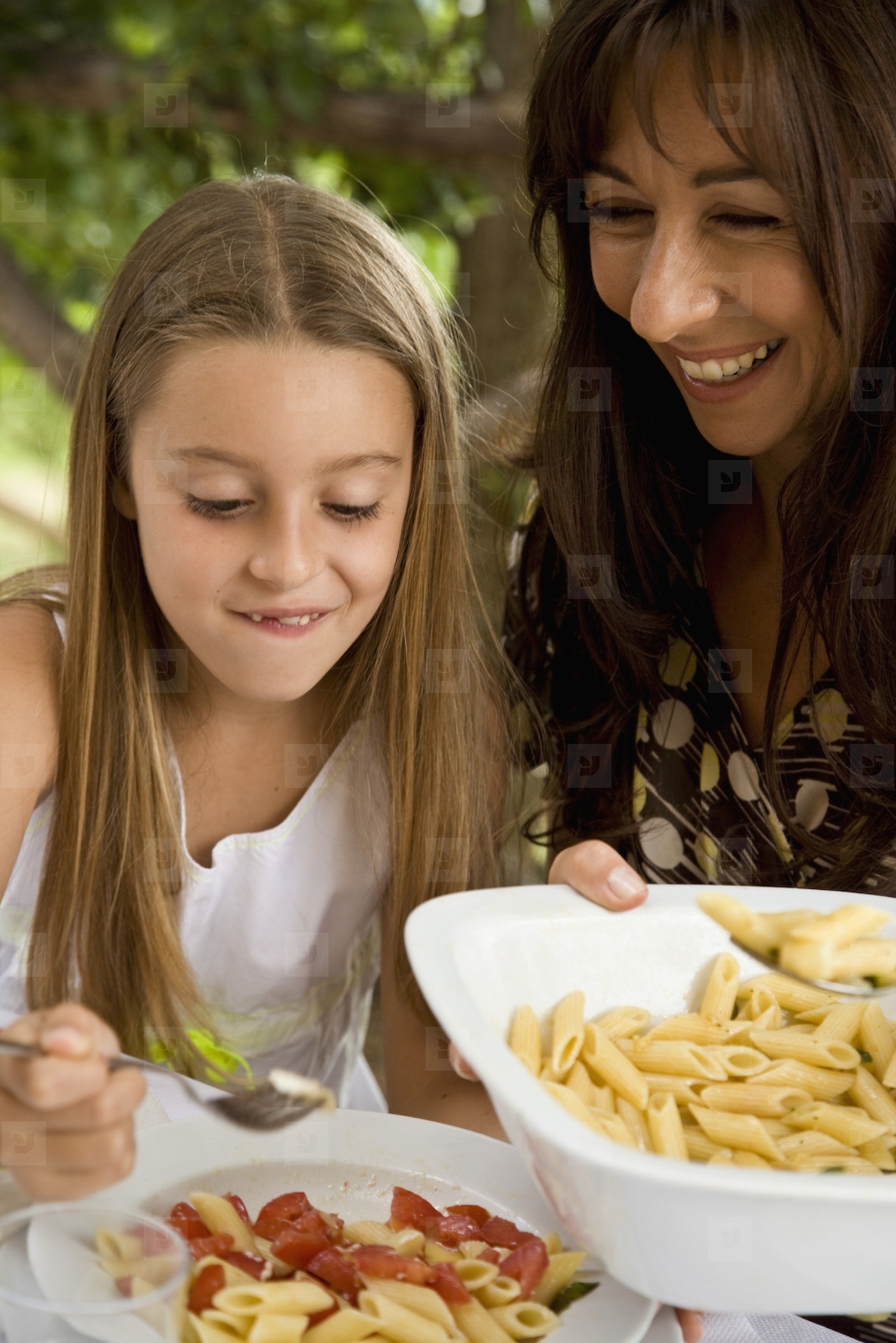 Mother serving pasta to daughter