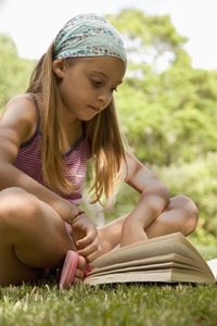 Portrait of young girl sitting cross legged reading book