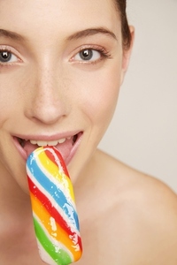 Young woman smiling and eating multicolored popsicle ice lolly