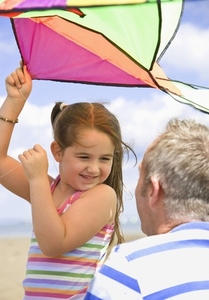Young girl holding kite and smiling to her father
