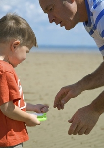Father talking to young boy holding kite flying line