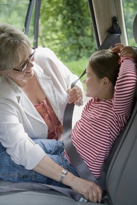 Grandmother adjusting seatbelt for granddaughter