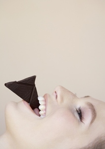 Close up profile of beautiful young woman eating chocolate