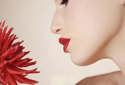 Close up of young beautiful woman inhaling red dahlia