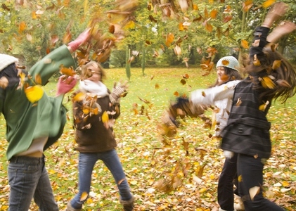 Young girls playing with leaves in the park