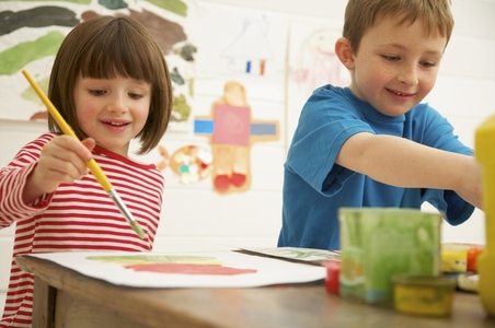 Portrait of young boy and young girl painting and smiling