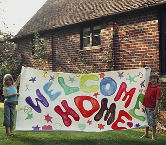 Portrait of two young children holding colorful welcome home sign