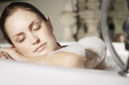 Woman relaxing her head against edge of bathtub