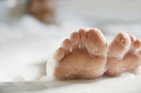Close up of woman feet covered in foam coming out of bathtub