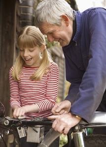 Young girl helping grandfather repairing motorbike