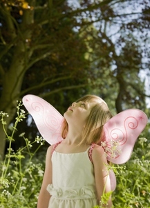 Portrait of a young girl in a fairy costume standing in a garden looking up