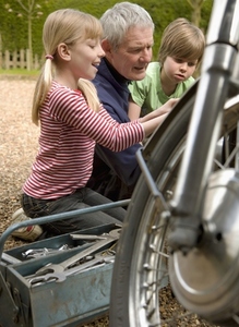 Grandchildren helping grandfather repairing motorbike