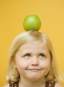 Girl with a green apple on top of her head looking up